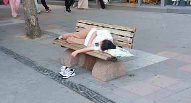 Sıcaktan bunalan genç gölgelik bankta yastıkla beraber uyudu