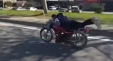 Plakasız motosiklet sürücüsü ellerini bırakıp motorun üzerine yatarak ilerledi
