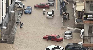 Yağmurda mahsur kalan motosikletli çareyi otomobilin üzerine çıkmakta buldu