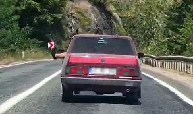 Ayaklarını camdan sarkıtarak trafiği tehlikeye attı