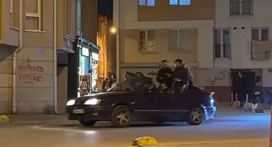 Seyir halindeki otomobillin bagajına ters oturan şahıs dikkat çekti